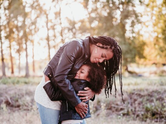 Mother embraces her child in a park | Wahl & Holland